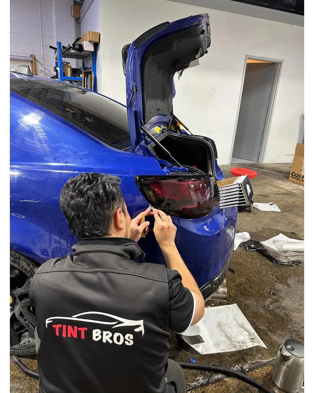 A Tint Bros technician at work on a customer's vehicle in the bay