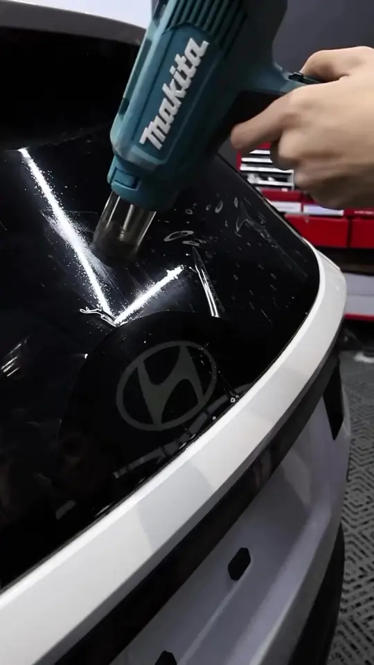 Installer heat-shrinking window tint film to the shape of the glass